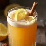A close-up of a glass of the Brazilian Mounjaro drink with lemon slices and cinnamon sticks. WP